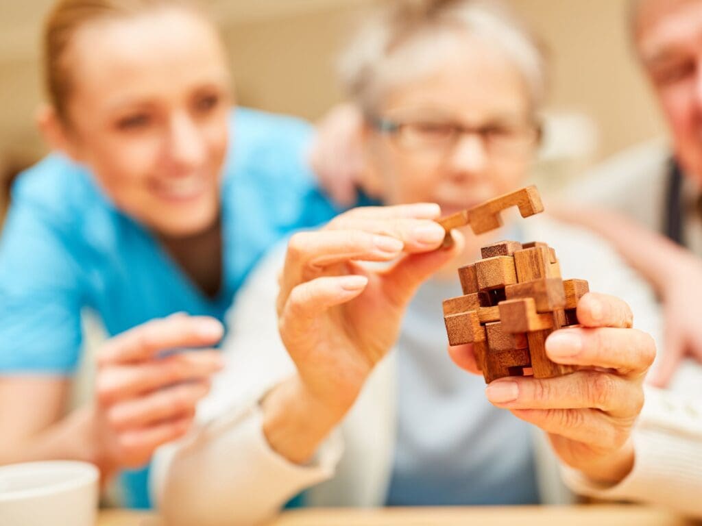 Lady with Alzheimers playing a game. It is a wooden interlocking puzzle that should help her with her memory function and prevent deteriation over time