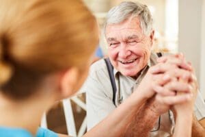 An elderly man holding hands with a carer