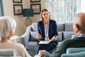 A professional caregiver running over a care plan with an elderly couple.