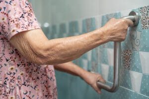 Living with dementia: our dementia home safety checklist. A Senior or elderly older lady woman patient using toilet bathroom handle